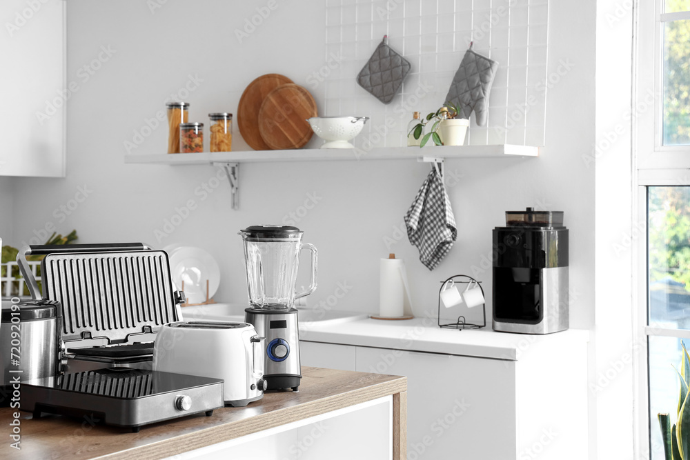 Set of modern appliances on wooden table in contemporary kitchen - obrazy, fototapety, plakaty 