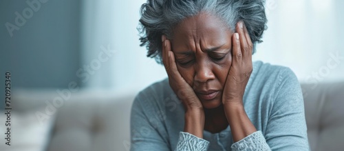Senior woman black people with depression sitting with her head in her hands at home