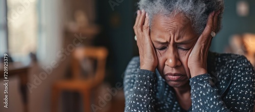 Senior woman black people with depression sitting with her head in her hands at home photo