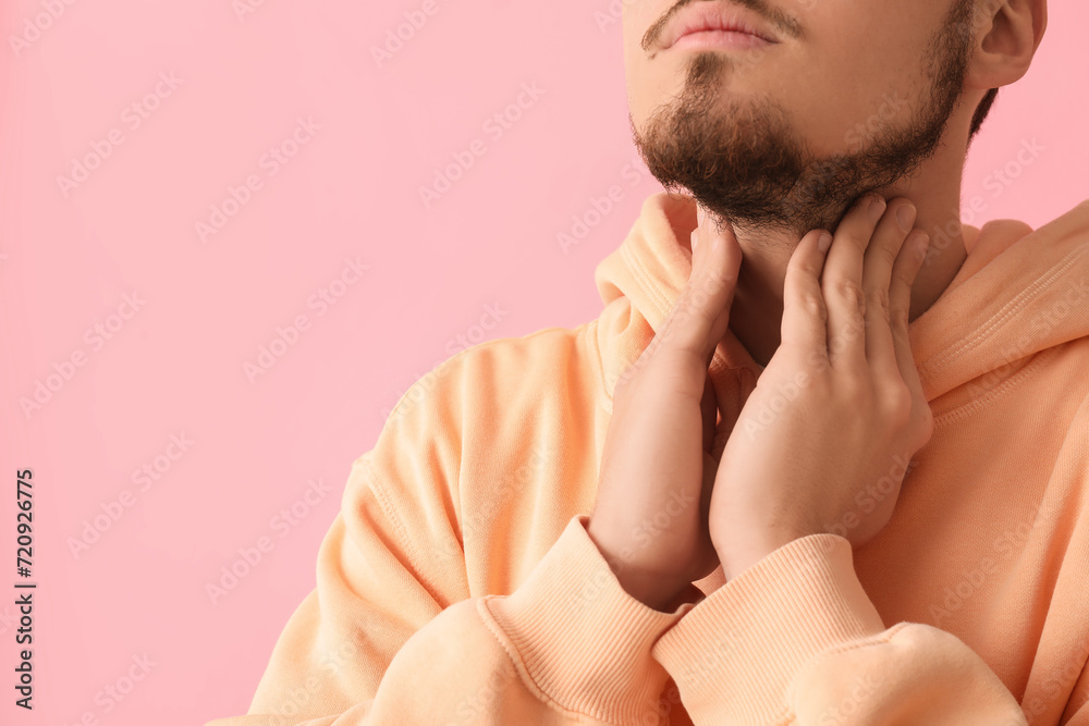 Fototapeta premium Young man with thyroid gland problem on pink background, closeup