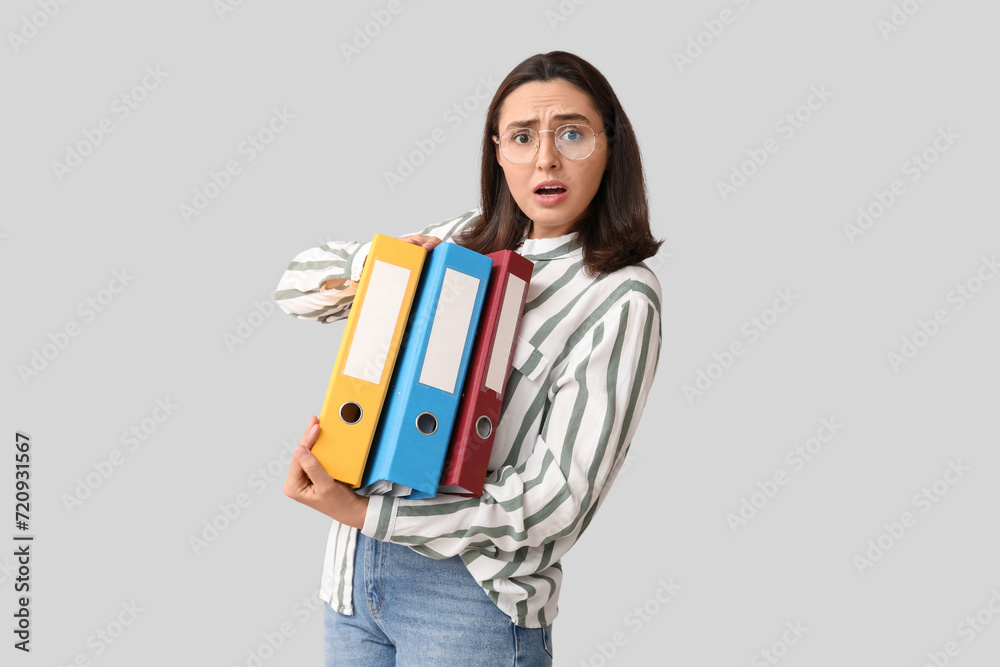 Stressed young businesswoman with document folders on light background Stressed young businesswoman with document folders on light background