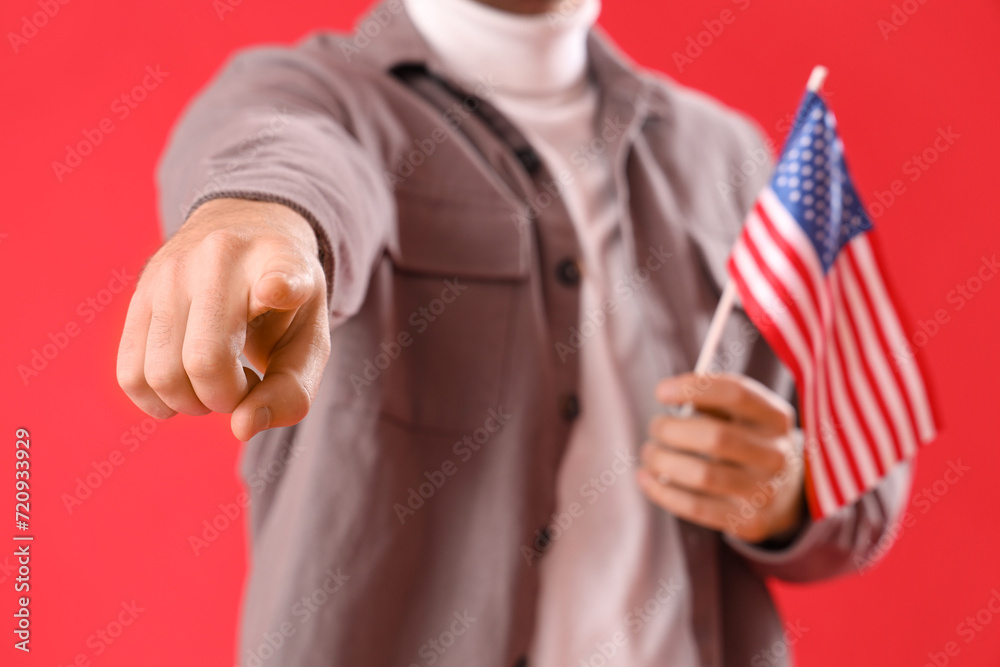 Young man with USA flag pointing at viewer on red background, closeup. Accusation concept