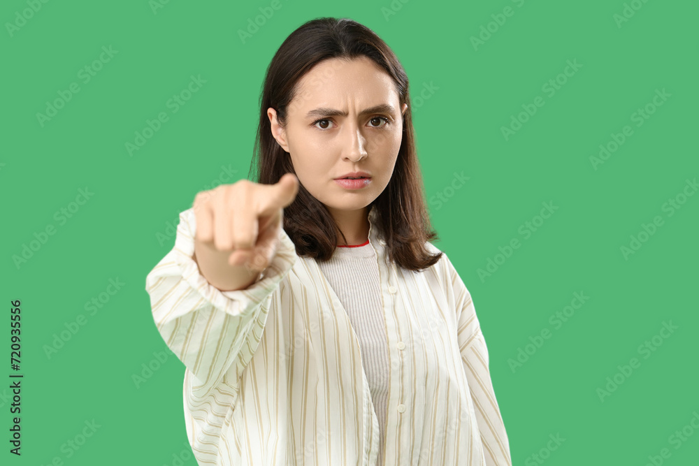 Young woman pointing at viewer on green background. Accusation concept Young woman pointing at viewer on green background. Accusation concept