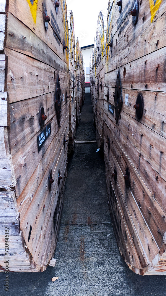 a narrow tunnel of wooden barrels with yellow and black labels