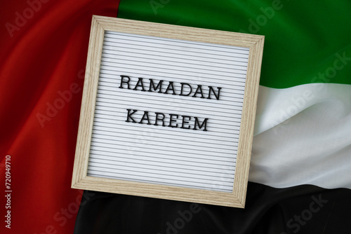 Message RAMADAN KAREEM - happy holidays waving UAE flag on background concept. Commemoration Day Muslim Greeting card advertisement. Blessed holy month holiday