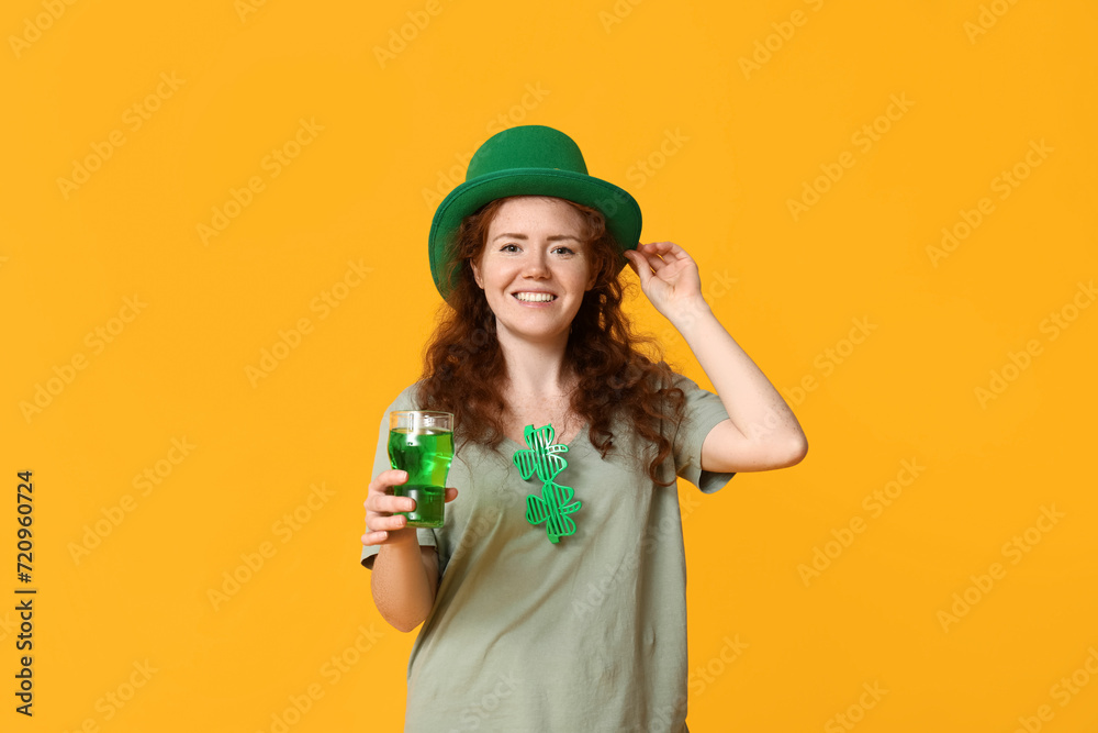 Young redhead woman in hat with beer on yellow background. St. Patrick's Day celebration Young redhead woman in hat with beer on yellow background. St. Patrick's Day celebration