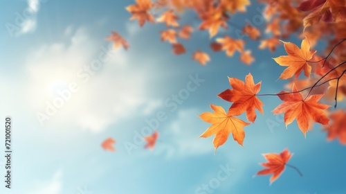 Vibrant orange autumn leaves fall gracefully against a bright blue sky with soft clouds and sunlight.
