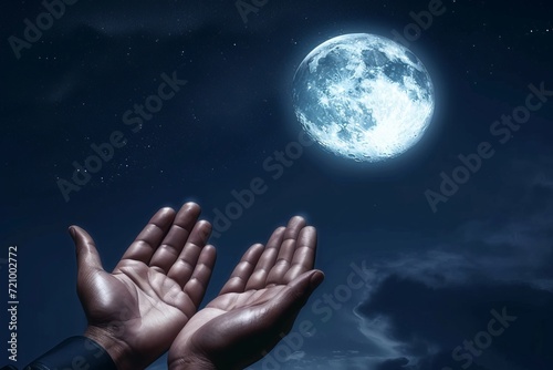 Moslem hand open and praying for dua under the full moonlight at night