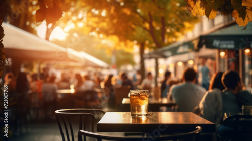 A refreshing glass of iced beverage on a table with a blurred background of a bustling outdoor cafe scene.