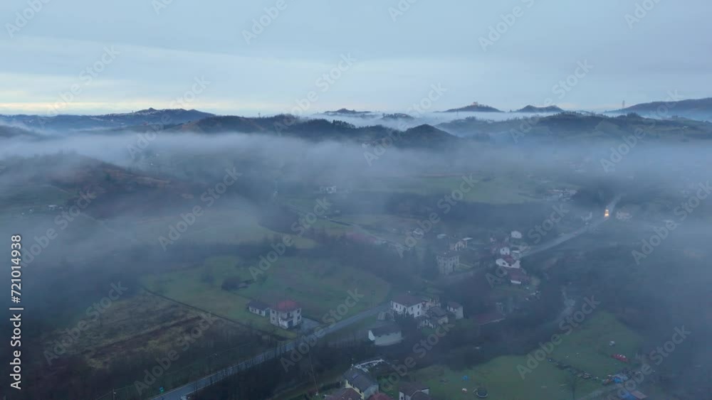 Mist hovering over hilly village countryside landscape at dawn, Italy.