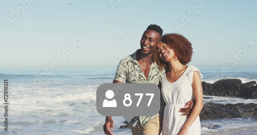Profile icons with increasing numbers against african american couple walking on the beach