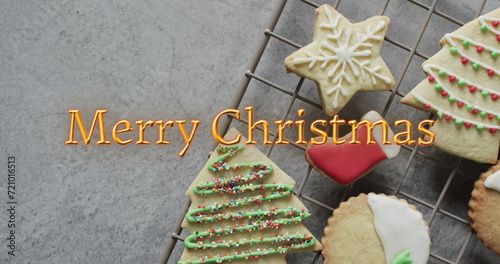Merry christmas text in orange over decorated on christmas cookies