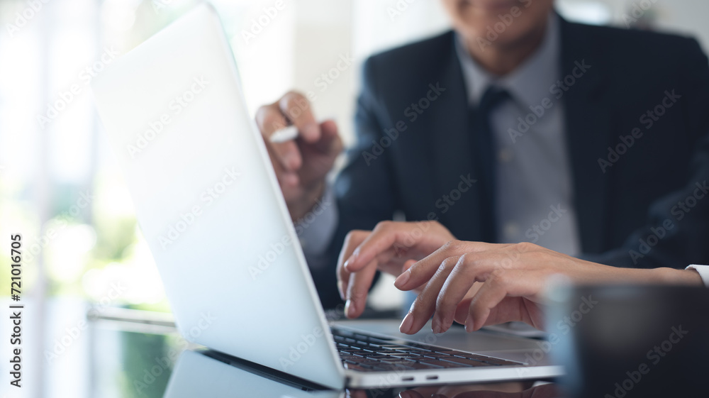 Two asian business persons working together on laptop at office. Businessman brainstorming, having a discussion with his colleague about work project,  Business teamwork - obrazy, fototapety, plakaty 