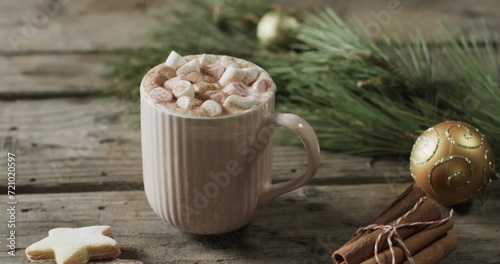A mug of hot chocolate topped with marshmallows sits on a wooden table