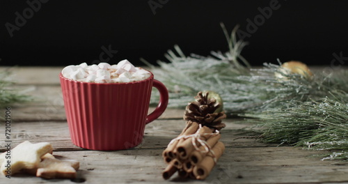 A red mug filled with hot chocolate sits on a wooden surface