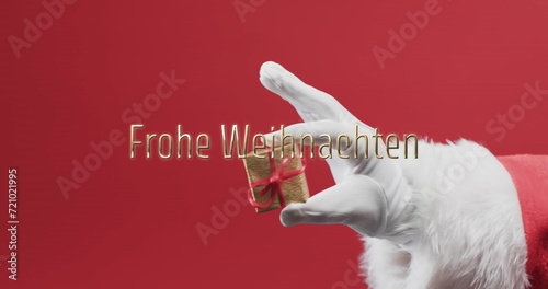 Frohe weihnachten text over hand of father christmas holding small gift on red background