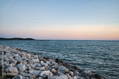 a person walking on some rocks by the water at sunset © Wirestock