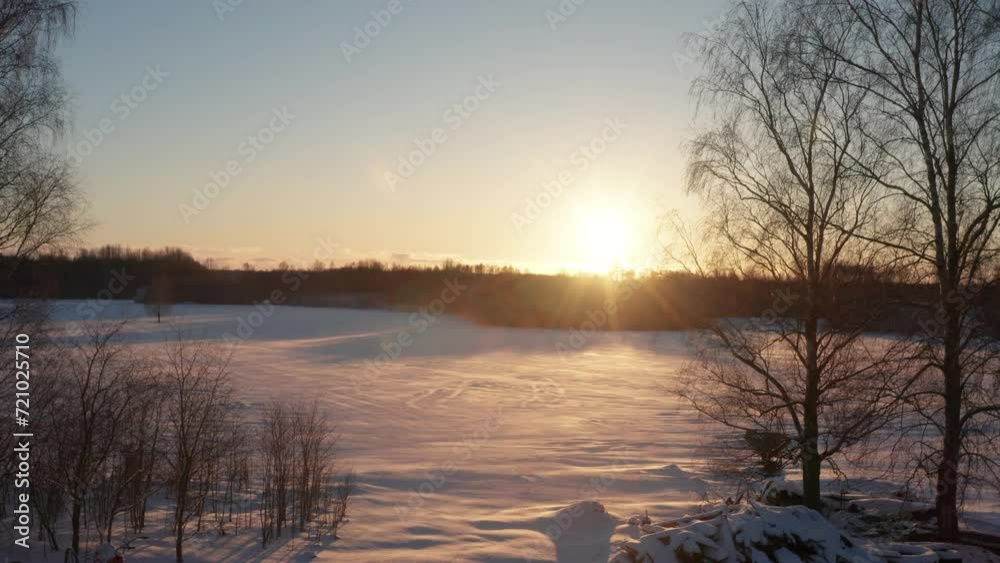 Illuminated snowy farmland reveal during bright winter sunset above forest Illuminated snowy farmland reveal during bright winter sunset above forest