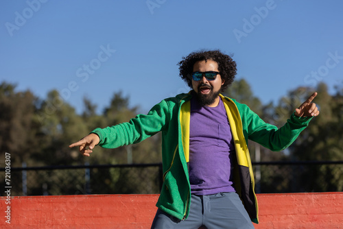Young Mexican man with curly hair, dancing happily in a park in Mexico,happiness and freedom concept © Teran