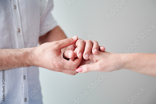 Close up of two hands engaging in delicate touch. Man's and woman's hands on white neutral background. Husband holding hand of his lovely wife. Concept of love, intimacy, support, and trust.