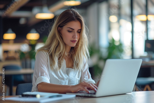 Focused Woman Working on Laptop in Office © Chanakan