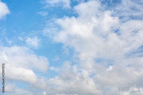 blue sky with fluffy white clouds background, creating serene and open canvas. gentle dance of clouds complements vivid azure backdrop, forming peaceful and harmonious celestial display