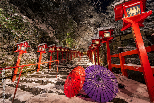 Kyoto, Japan. Kifune shrine traditional light pole in snowy winter night. Japanese umbrella on the stone stairs. Concept of Japanese culture. photo