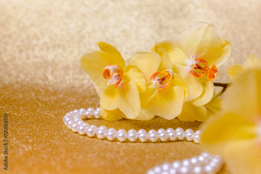 yellow Orchid and pearl necklace on a shiny gold background yellow Orchid and pearl necklace on a shiny gold background