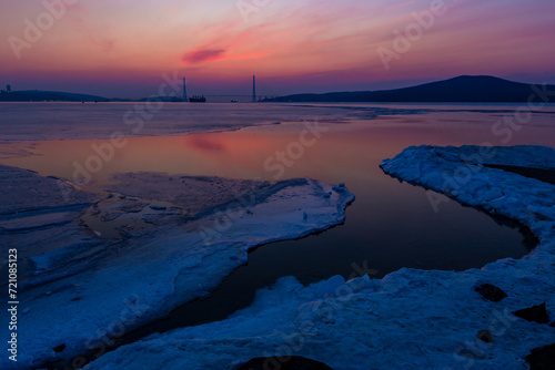 Winter Vladivostok. Russian bridge at dawn. A bright red sun rises behind the bridge. Eastern Bosphorus Strait.