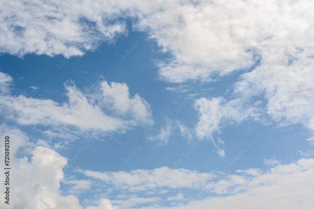 Obraz premium blue sky backdrop adorned with fluffy white clouds sets serene and open canvas. gentle dance of clouds complements vivid azure background, peaceful and harmonious celestial