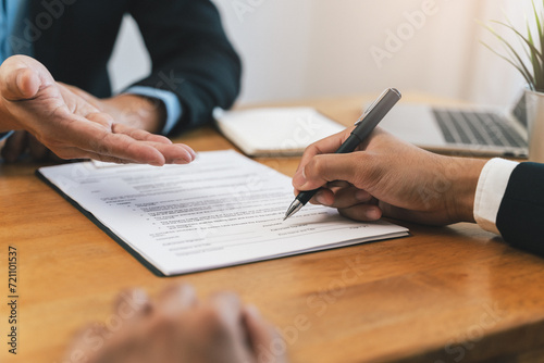 businessman sitting at desk holds pen signing contract paper, lease mortgage, employment hr or affirm partnership