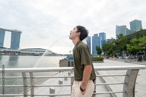 Merlion fountain in front of the Marina Bay with young asian man tourist.