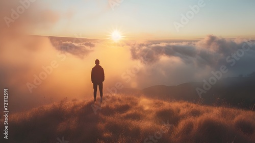 Lonely man standing on top of the mountain during sunset.