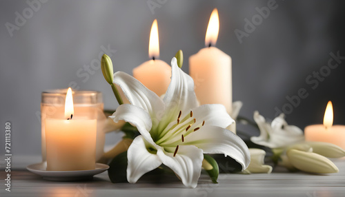 White lily and blurred burning candles on table in darkness