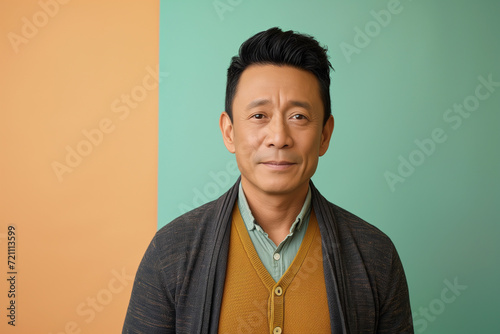 Portrait young confident smart Asian man look at camera and smile. handsome young man standing against a colorful background. Handsome man has nice smile. Attractive man wear casual photo