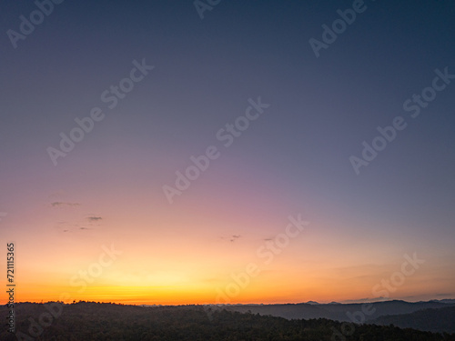 Aerial view A breathtaking sunset paints the sky with vibrant hues of orange and red, .casting a warm glow over the majestic mountains in a tranquil evening landscape.