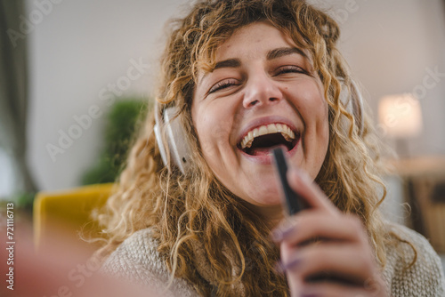 One woman with headphones at home listen music online happy smile sing photo
