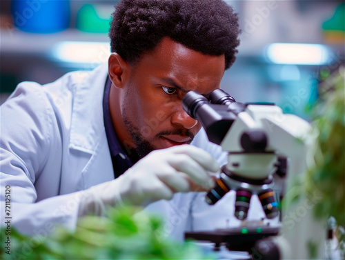 Concentrated African American scientist using a microscope for plant analysis. Bioenergy, biomass, environmental biology concept