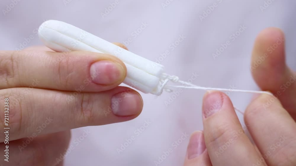 Woman hands holding white cotton sanitary tampon for monthly period close up