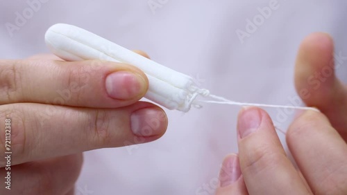 Woman hands holding white cotton sanitary tampon for monthly period close up