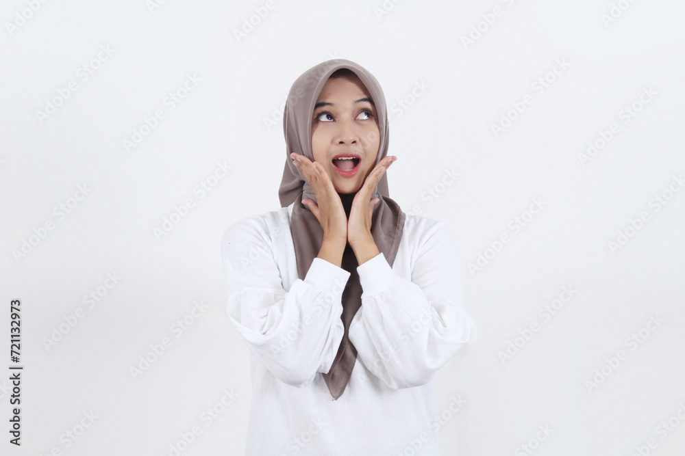 Beautiful Asian Muslim woman is holding her chin with both open hands with a surprised face facing upwards and an open mouth showing teeth Beautiful Asian Muslim woman is holding her chin with both open hands with a surprised face facing upwards and an open mouth showing teeth