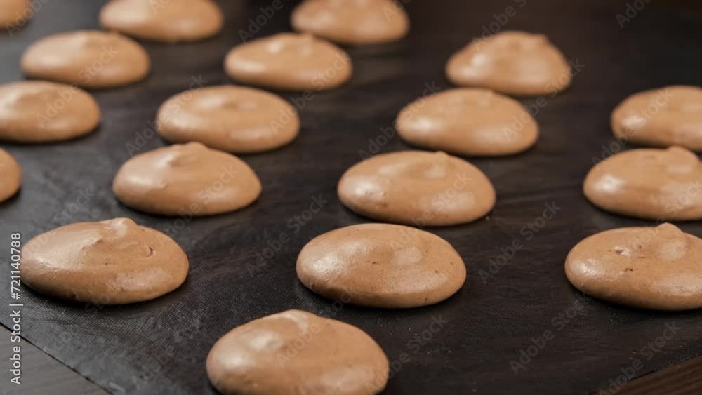 Extruding chocolate macaroons from piping bag. Chef making macaron dessert. Baking concept. Making French dessert. Close-up in 4K, UHD Extruding chocolate macaroons from piping bag. Chef making macaron dessert. Baking concept. Making French dessert. Close-up in 4K, UHD