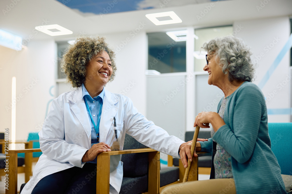 Happy African American doctor and her senior female patient talking in waiting room at medical clinic. Happy African American doctor and her senior female patient talking in waiting room at medical clinic.