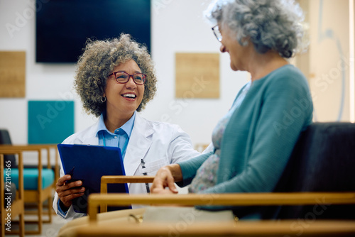 Happy female doctor communicating with senior woman at medical clinic. photo