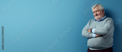 Elderly overweight man with crossed arms on blue background