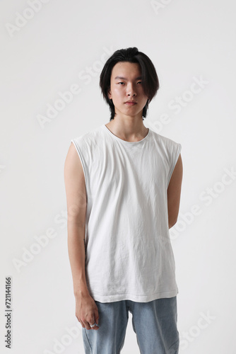 Confident and young Asian man posing indoor over white wall. Vertical mock-up.