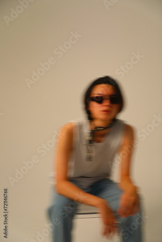 Handsome Asian man wears sunglasses posing indoor over white wall. Vertical.