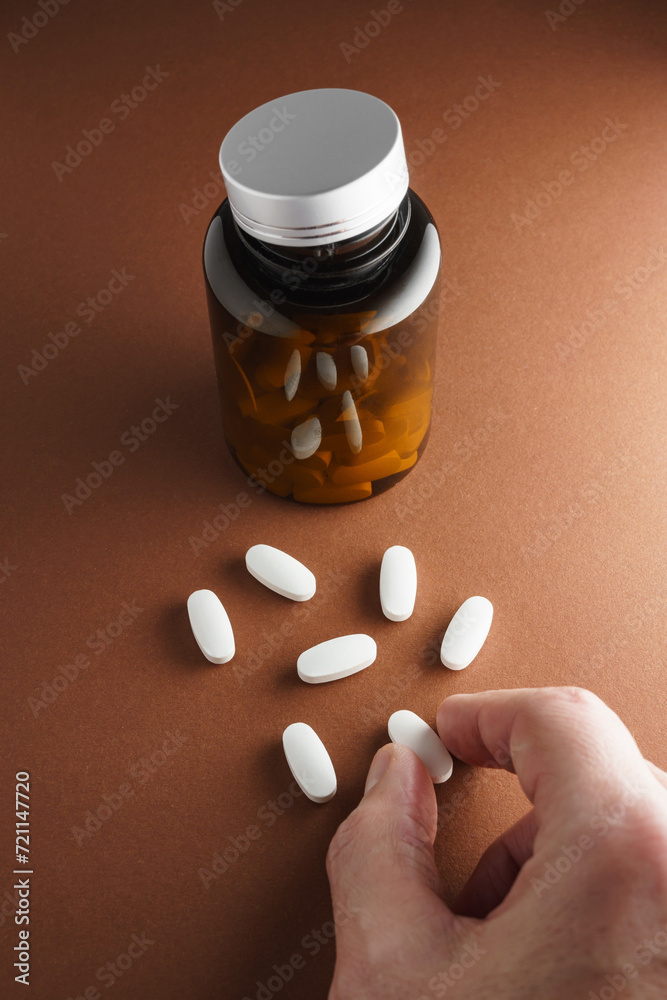 Białe tabletki rozsypane luzem z butelki z lekami - obrazy, fototapety, plakaty 