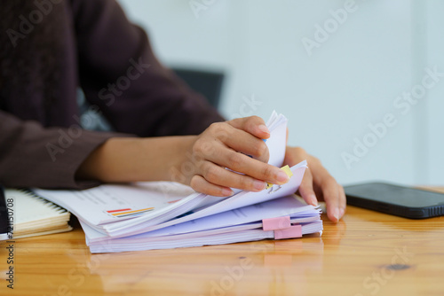 Close-up hand of Asian businesswoman arranging documents on her desk.