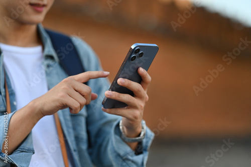 Close-up image of A backpacked male tourist checking his mobile phone Tha Phae gate, at Chiangmai on background with copy space